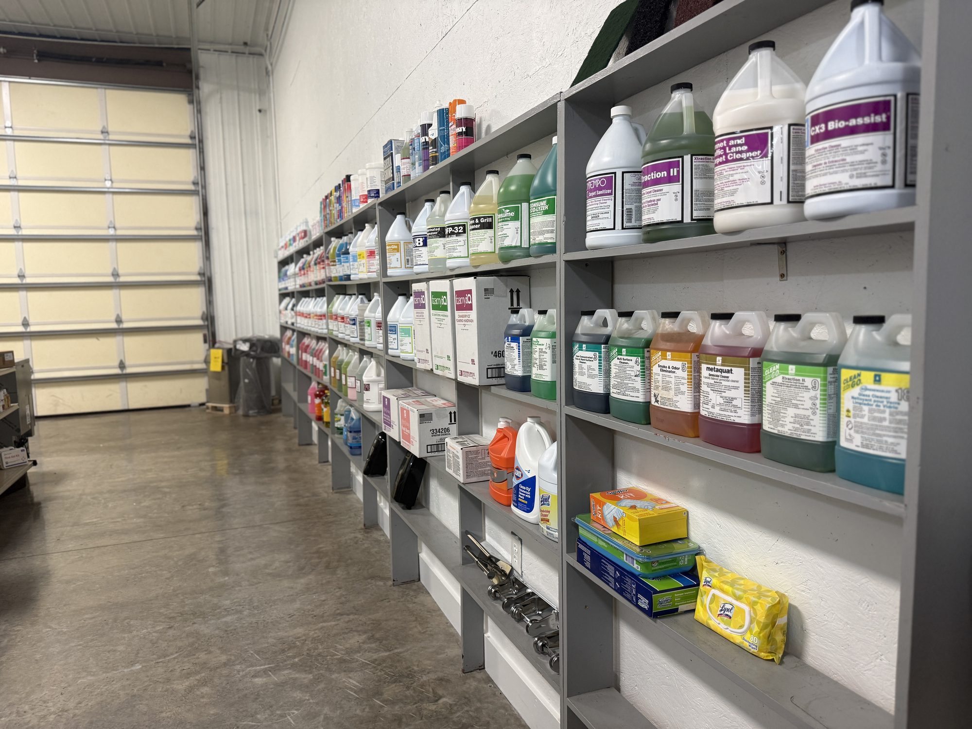 Rows of cleaning chemical bottles and jugs on warehouse shelving